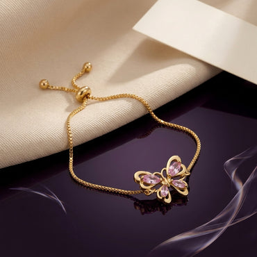 Gold-Tone Pink CZ Butterfly Adjustable Bracelet product shot on dark surface with cream fabric