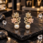 Gold-tone floral earrings with clear upper flowers, pale-pink lower flowers, clear-accent open leaf details and round white pearl-look drops.
