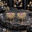 Pair of silver-tone starburst earrings with faceted pink centres and tapered rays covered in clear sparkling accents.