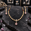 Gold-tone necklace with rounded floral clusters, leaf-shaped links and a pink teardrop beneath a flower centre, with matching floral drop earrings.