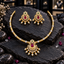 Gold-tone segmented necklace and matching earrings with pink teardrop centres, small green details, clear accent borders and cream pearl-look hanging drops on dark slate.