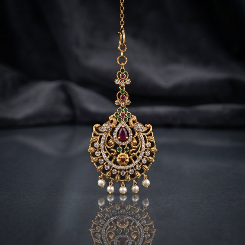 Gold-tone Rajwari bindiya with red and green accents, clear stones, and dangling white beads.