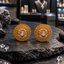 Gold-tone round Rajweri earrings with clear-looking faceted centres, layered floral petals, curling scrollwork and raised bead-style borders.