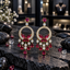 Pair of gold-tone circle chandelier earrings with red butterfly details, clear sparkling accents and graduated red teardrop drops.