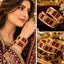 Gold-tone bangle pair with deep red decorative panels, green-edged square clear accents and intricate filigree-style sections.