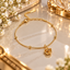 Gold-tone bracelet with a layered rose charm, spaced round beads, a fine textured chain, clasp and extension chain.