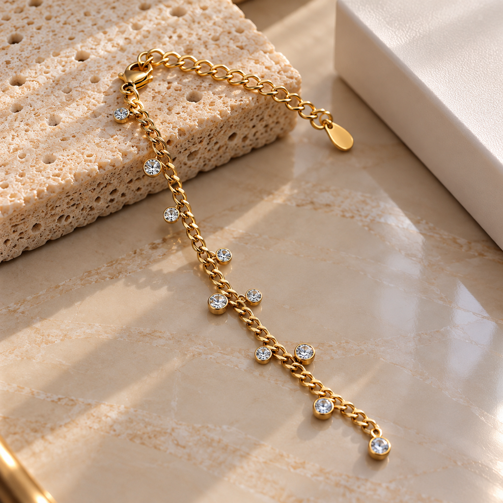 Gold-tone curb-style chain bracelet with mixed-size dangling round clear accents, circular settings, a lobster-style clasp and extension chain.