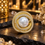 Gold-tone circular statement ring with a large round white pearl-look centre, surrounding clear-accent rows and open spaces around curved supports.