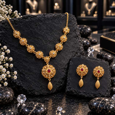 Gold-tone floral filigree necklace and matching earrings with ruby-coloured centres, round openwork necklace links and elongated textured drops.