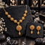 Gold-tone floral filigree necklace and matching earrings with ruby-coloured centres, round openwork necklace links and elongated textured drops.
