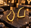 Pair of gold-tone sculptural open-hoop earrings with smooth polished-looking surfaces, curved sides and rounded angular lower outlines.
