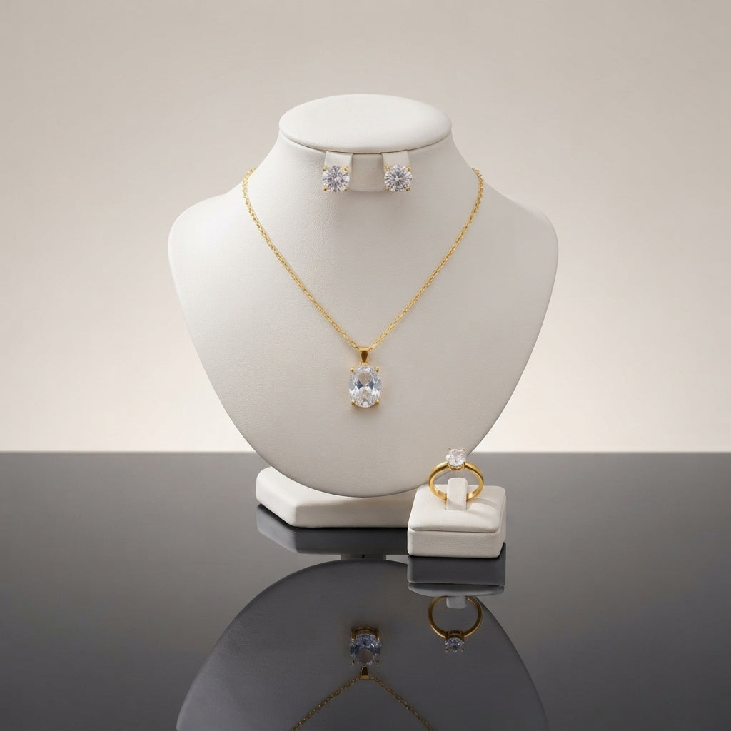 Gold-tone set displayed with a clear-stone pendant necklace, stud earrings, and matching ring.