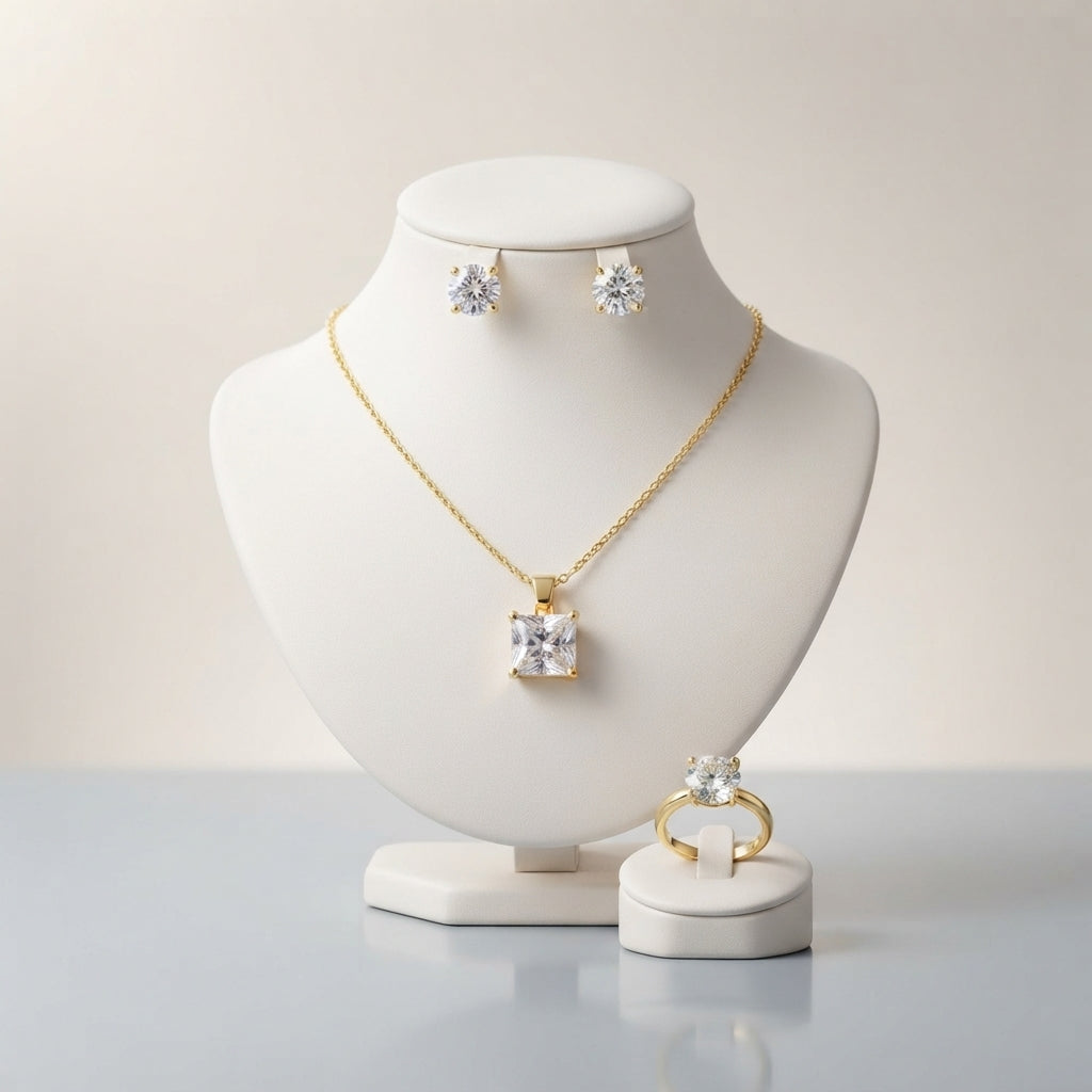 Gold-tone set displayed with a square-cut pendant necklace, round stud earrings, and a matching ring.