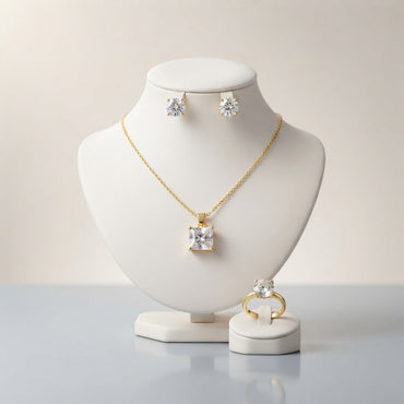 Gold-tone set displayed with a square-cut pendant necklace, round stud earrings, and a matching ring.