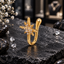 Gold-tone nose pin with a pointed starburst motif, clear accents, raised texture details and an open U-shaped body with a rounded opposite end.
