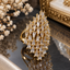 Gold-tone statement ring with staggered rows of tapered clear accents in prong-style settings, forming an elongated pointed front.