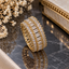 Gold-tone band ring with a central row of rectangular clear accents, two outer rows of round clear accents and gold-tone prong-style settings.