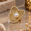 Gold-tone statement ring with a round white pearl-look centre, radiating openwork lines and an irregular wavy border lined with clear accents.