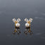 Pair of gold-tone earrings with white pearl-look round beads and clear faceted petal-shaped accents.