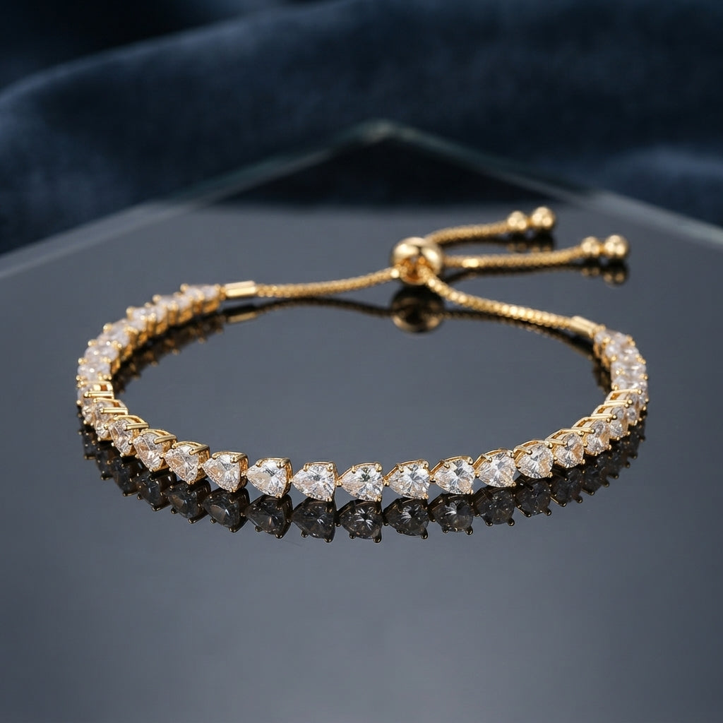 Gold Trillion CZ Tennis Adjustable Bracelet — 22K gold-tone full tennis bracelet with continuous trillion triangle cut white CZ chevron band in 3-prong gold settings, graduating stone size, and adjustable sliding gold ball closure, on dark hexagonal mirror tray with navy velvet backdrop