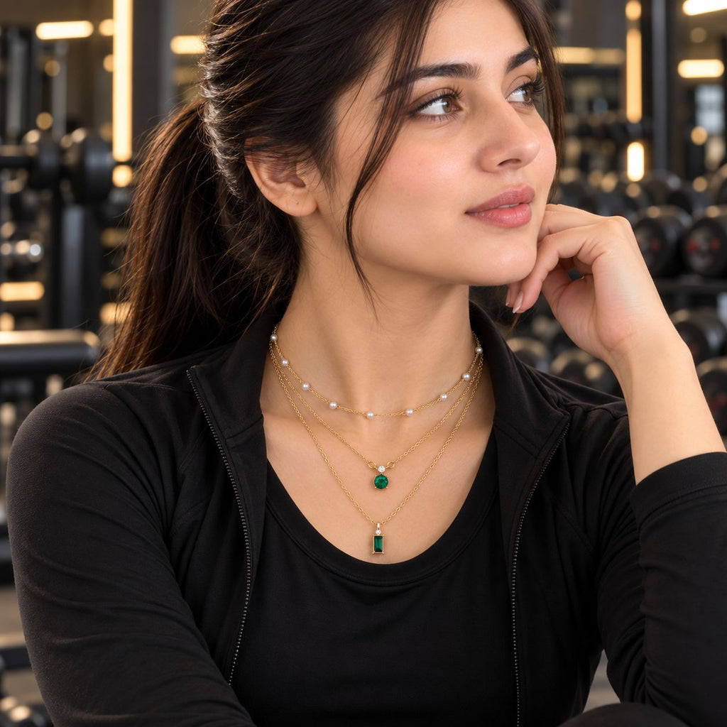 Gold Triple-Layer Pearl Station & Emerald CZ Dual Pendant Layered Necklace Set worn by model in black gym outfit at gym setting