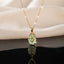 Gold Tulip Enamel Oval Pendant Necklace in mint green enamel flat lay on black mirror surface with white silk backdrop showing raised 3D gold tulip motif on mint green oval pendant with gold cable chain and sparkle effect with mirror reflection below