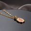 Gold Tulip Enamel Oval Pendant Necklace in blue grey enamel flat lay on black mirror surface with dark and beige fabric backdrop showing raised 3D gold tulip motif with CZ accents on blue grey oval pendant with gold cable chain and sparkle effect with mirror reflection below