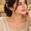 Gold Tulip Pearl Pendant Necklace worn by bridal model in cream pearl-embroidered lehenga with gold lantern and white floral bokeh backdrop