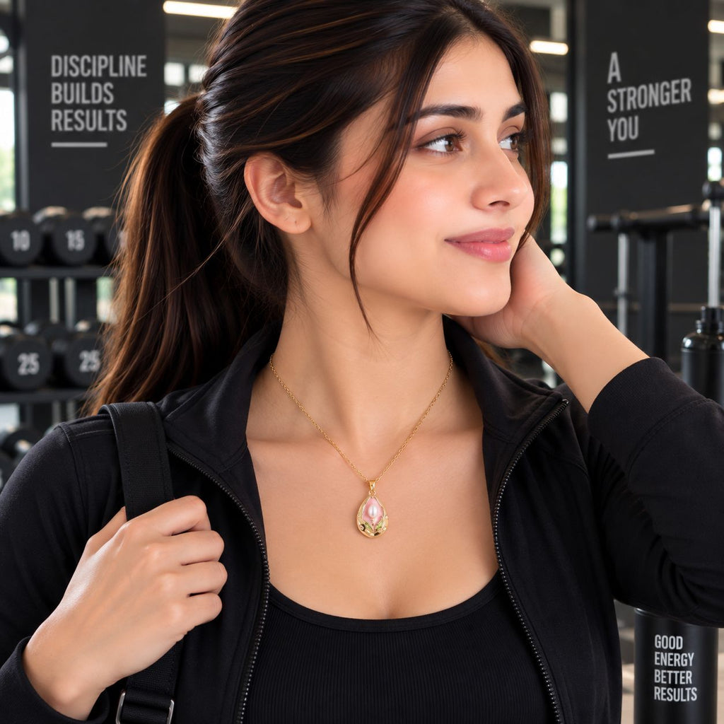 Gold Tulip Pearl Pendant Necklace worn by model in black gym jacket at gym setting with dumbbell rack backdrop