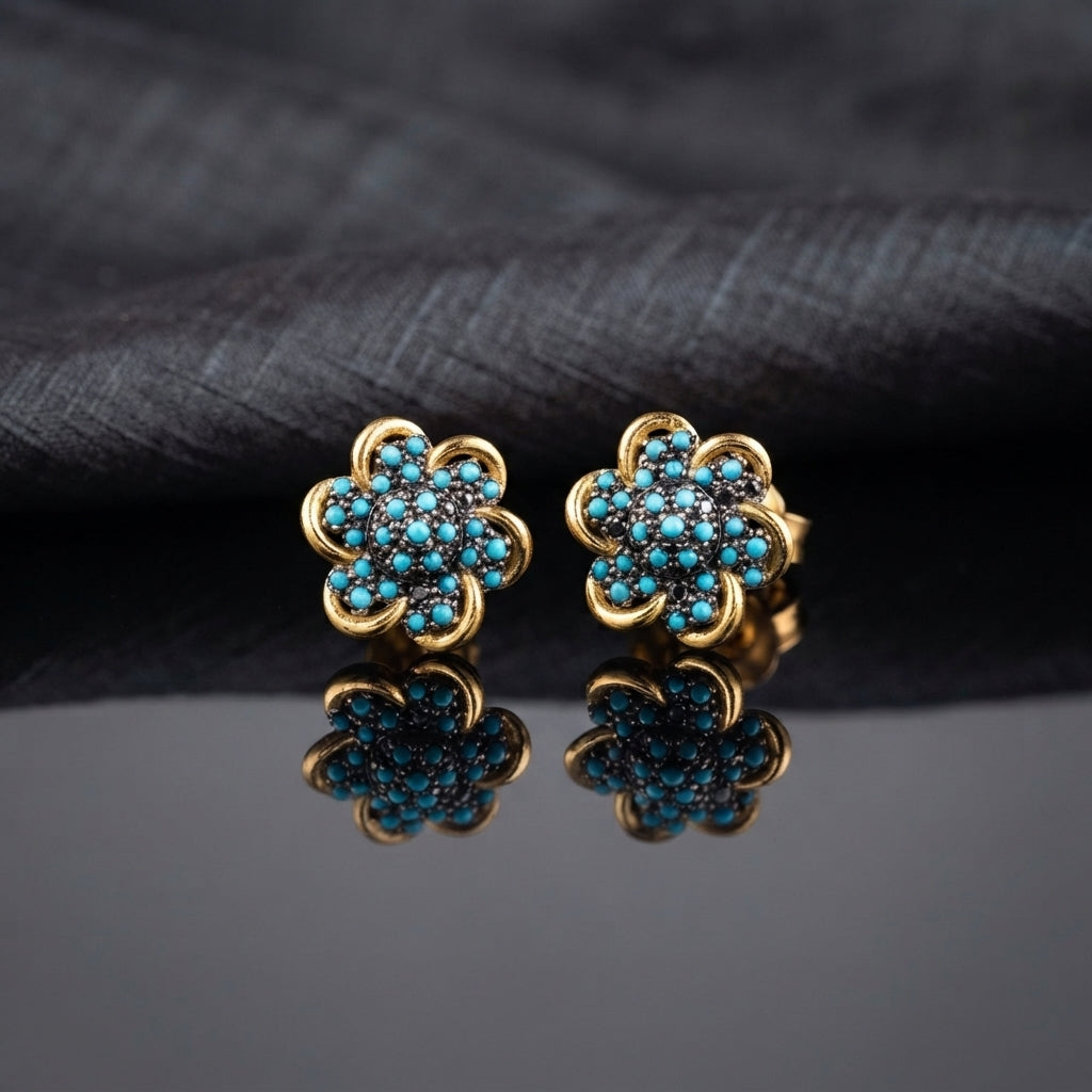 Gold Turquoise Pavé Flower Stud Earrings on dark grey mirror surface with dark grey fabric drape backdrop