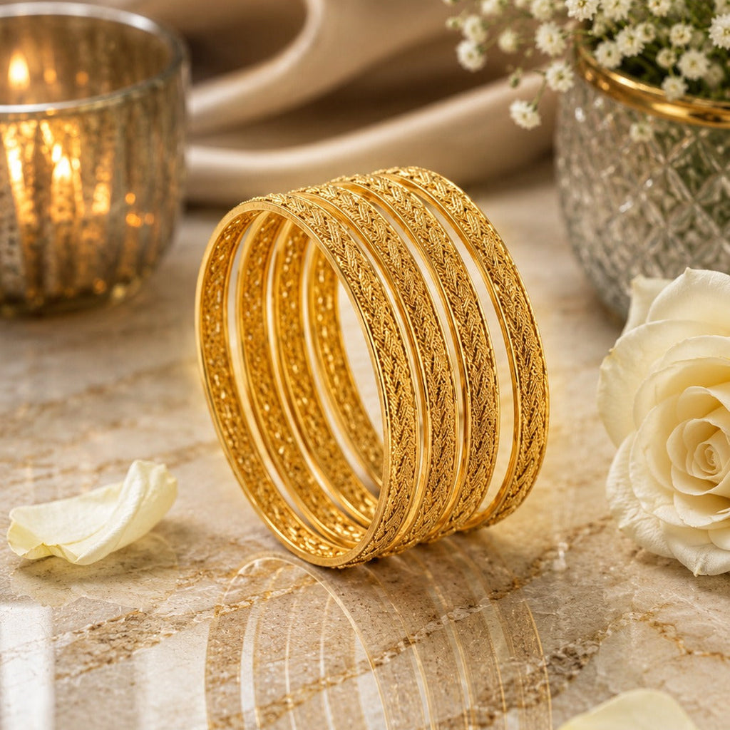Gold-Tone Twisted Rope Textured Bangle Set of 4 on marble surface with candle, white rose and baby's breath flowers backdrop