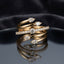 Gold White CZ Pear Multi-Spiral Wrap Coil Cocktail Ring — five-coil 22K gold serpenti wrap band with large pear CZ claw accents at top and base and full round white CZ micro-pavé middle coil, luxury product flat-lay on round mirror tray with dark charcoal silk backdrop