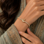 Woman wearing gold-tone CZ pave swan tennis bracelet with micro-pave swan centerpiece and round CZ tennis chain styled with a grey silver embroidered Pakistani formal outfit
