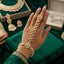 Kundan Pearl Hath Phool Bracelet Ring Silver lifestyle shot worn on model hand over green velvet cushion with silver embroidered green suit showing rhodium silver-tone kundan polki flower wrist station with pear CZ petals faux pearl drop hand chain and matching finger ring