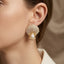 Micro Pavé CZ Seashell Faux Pearl Stud Earrings in silver-tone plating flat lay on dark grey mirror surface showing pair of fully CZ encrusted fan seashell studs with large round faux pearl in CZ cradle at base with mirror reflections below and grey silk backdrop