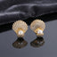 Micro Pavé CZ Seashell Faux Pearl Stud Earrings in silver-tone plating worn on model ear with beige stone background and teal blazer showing full CZ encrusted seashell design with large pearl at base