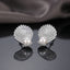 Micro Pavé CZ Seashell Faux Pearl Stud Earrings in gold-tone plating worn on model ear with beige warm background and cream outfit showing full CZ encrusted seashell design with large oval pearl at base