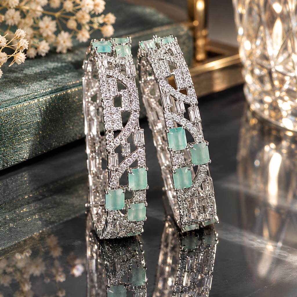 Pair of silver-tone-looking wide hoop earrings with mint-green accents, clear faceted details, and geometric openwork.