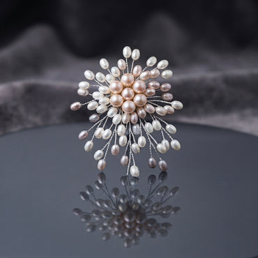 Multi-Tone Faux Pearl Starburst Spray Statement Brooch Pin flat lay on dark grey mirror surface with dark grey silk backdrop showing dandelion starburst spray brooch with round peach-pink faux pearl center cluster white oval pearl mid ring and mixed white lavender grey oval faux pearls on fine twisted silver-tone wire stems with mirror reflection below