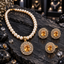 Cream pearl-look beaded necklace with golden-yellow oval pendant, matching earrings and ring, surrounded by clear decorative accents on dark slate.