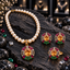 Cream pearl-look beaded necklace with golden-yellow oval pendant, matching earrings and ring, with pink-red, green and clear accents on dark slate.