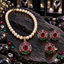 Cream pearl-look beaded necklace with red oval pendant, matching earrings and ring, with pink-red, green and clear border accents on dark slate.