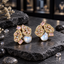 Pair of silver-tone cluster earrings with clear accents, sparkling openwork panels, rectangular details and white iridescent pearl-look centres.
