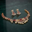 South Indian-style gold-tone floral necklace and matching drop earrings with green accents and pearl-look drops, displayed with decorative props.
