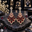 Pair of gold-tone chandelier earrings with pale pink accents, deep red teardrop drops and clear sparkling borders.