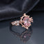Rose Gold Oval Morganite Crown Solitaire Ring in blush pink CZ on dark mirror surface with grey silk backdrop showing 18K rose gold-tone ornate open scrollwork crown setting holding faceted oval blush pink morganite CZ centre stone with 3+3 round white CZ shoulder clusters with mirror reflection below