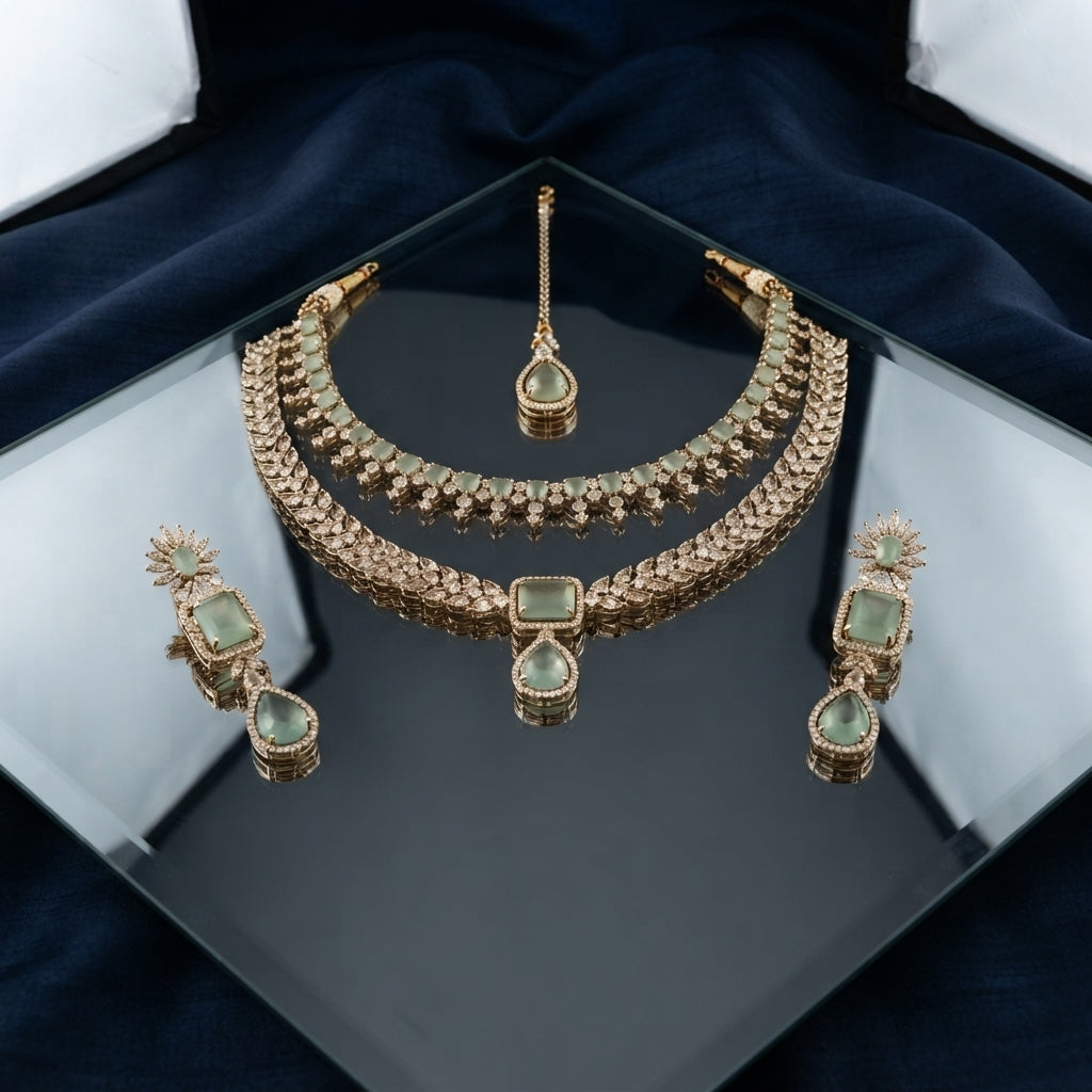 Rose Gold Sage Green Cabochon CZ Choker Necklace Drop Earrings & Maang Tikka Bridal Set on black mirror surface with dark navy blue silk drape backdrop in jewelry box presentation