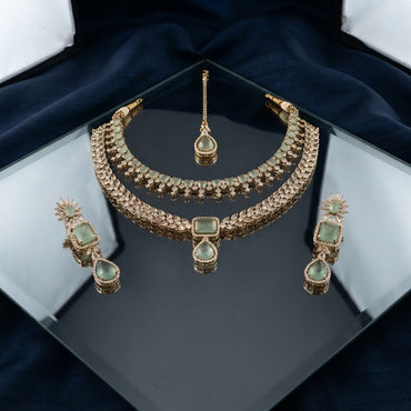 Rose Gold Sage Green Cabochon CZ Choker Necklace Drop Earrings & Maang Tikka Bridal Set on black mirror surface with dark navy blue silk drape backdrop in jewelry box presentation