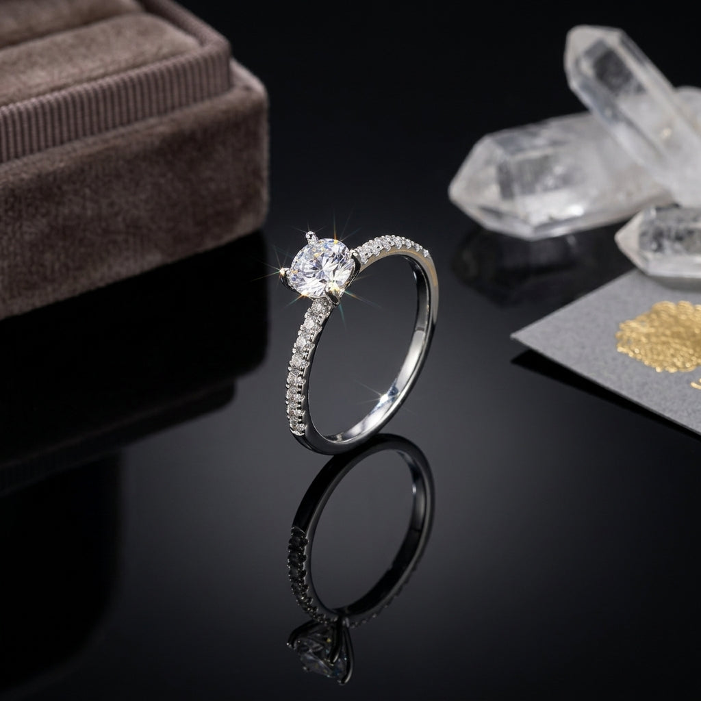 Silver-Tone 4-Prong Round CZ Solitaire Full Pavé Eternity Band Engagement Ring on black reflective surface with taupe velvet ring box and white quartz crystal clusters backdrop