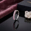 Silver-Tone 7-Stone Round Pink CZ Half Eternity Adjustable Band Ring on black reflective surface with mauve pink velvet fabric and navy blue ring box backdrop